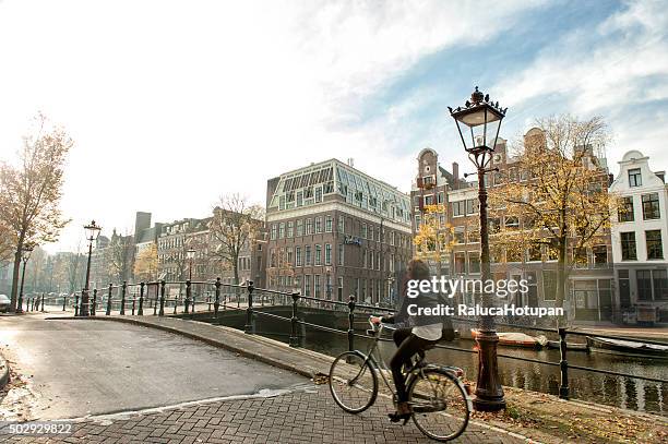 woman riding bicycle in amsteram - amsterdam autumn stock pictures, royalty-free photos & images