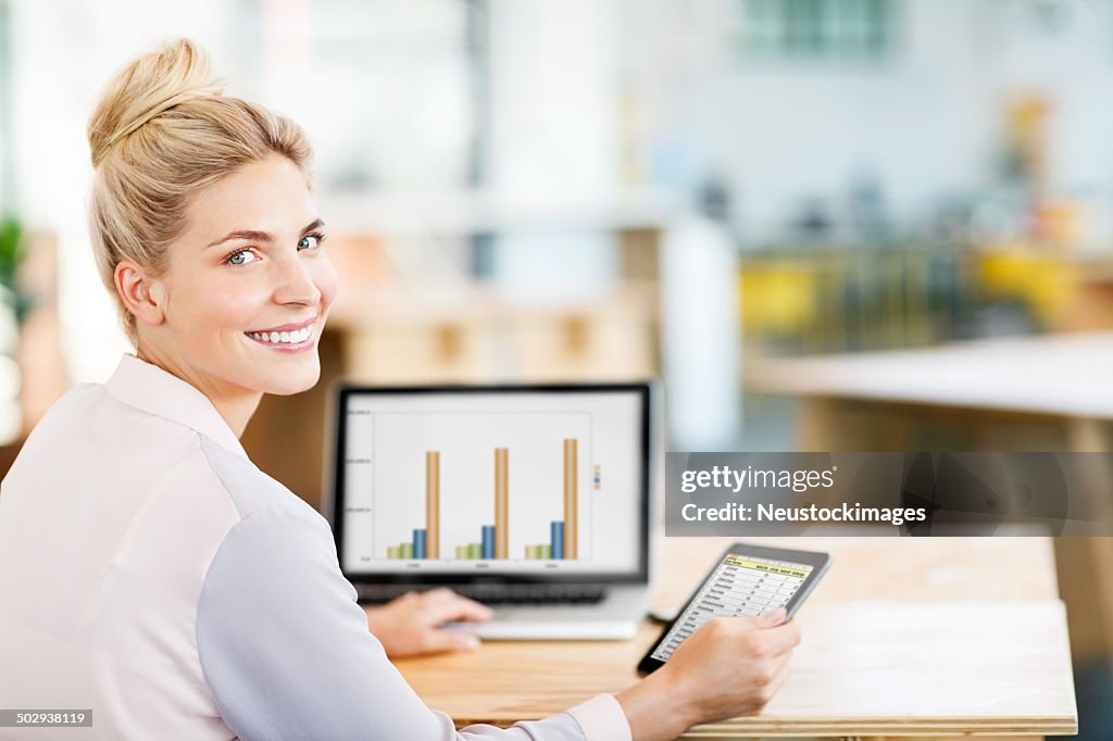 Entrepreneur Using Digital Tablet And Laptop At Desk In Office