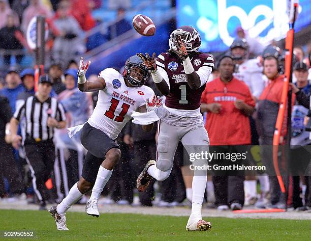 De'Runnya Wilson of the Mississippi State Bulldogs makes a catch against Juston Burris of the North Carolina State Wolfpack during the Belk Bowl at...