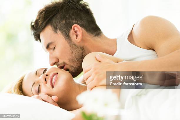mann küssen frau auf bett - good morning kiss images stock-fotos und bilder