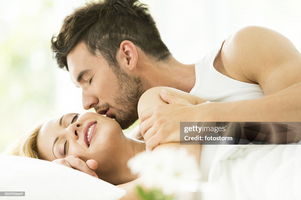 Man kissing woman in bed