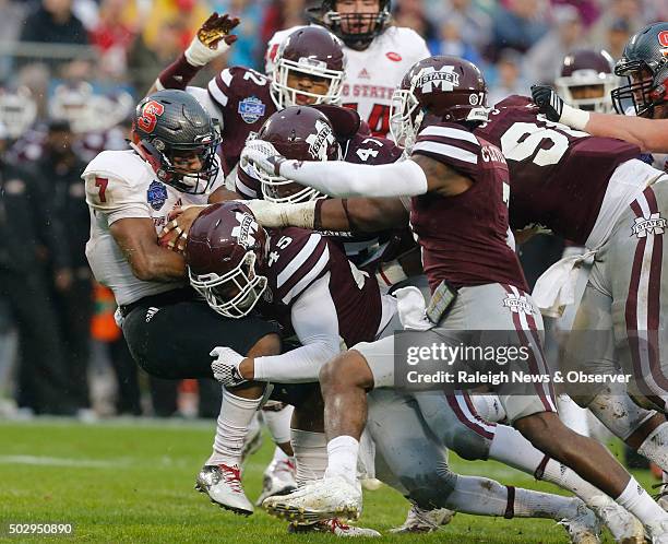 North Carolina State wide receiver Nyheim Hines is stopped by Mississippi State's J.T. Gray and A.J. Jefferson during the first half of the Belk Bowl...