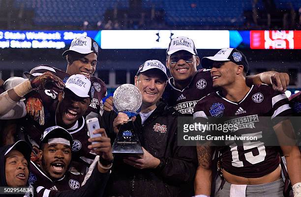 Head coach Dan Mullen and the Mississippi State Bulldogs celebrate with the trophy after a win over the North Carolina State Wolfpack during the Belk...
