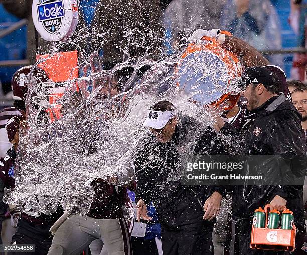 Players douse head coach Dan Mullen of the Mississippi State Bulldogs with water to celebrate a win against the North Carolina State Wolfpack during...