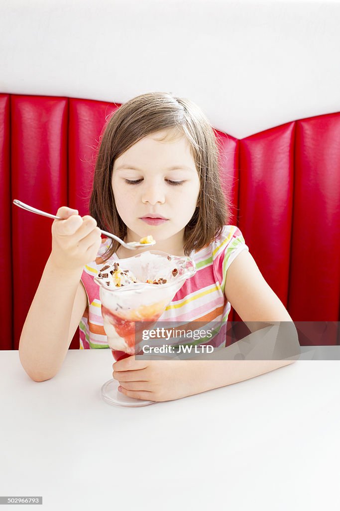 Young girl (10yrs) eating ice cream in diner