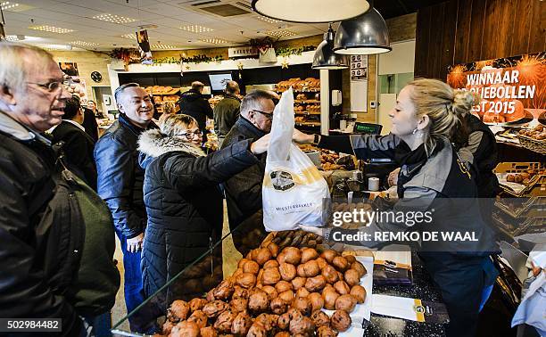 Customes buy "oliebollen" by donutmaker Richard Visser on December 31, 2015 in Spijkernisse. An oliebol is a donut-like product, traditionally made...