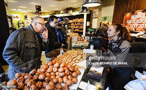 Man buys "oliebollen" by donutmaker Richard Visser on December 31, 2015 in Spijkernisse. An oliebol is a donut-like product, traditionally made and...