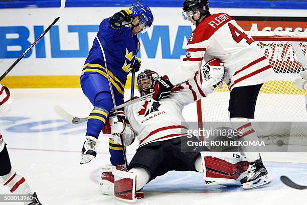 Canada's goalie Mackenzie Blackwood gets pinned between Sweden's Axel Holmstrom and Canada's Haydn Fleury during the 2016 IIHF World Junior U20 Ice...