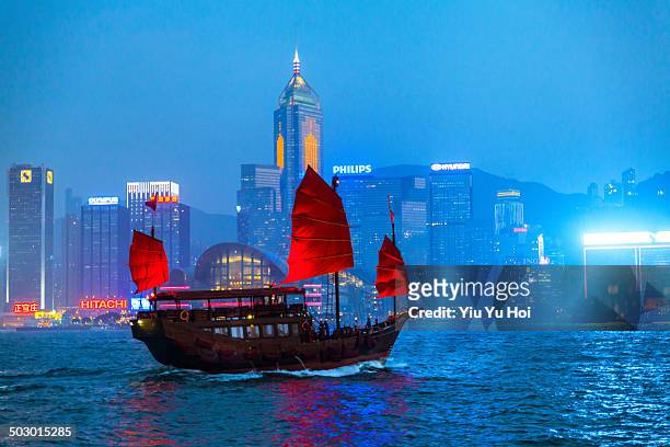 chinese junkboat sailing across victoria harbour - victoria harbour hong kong photos et images de collection