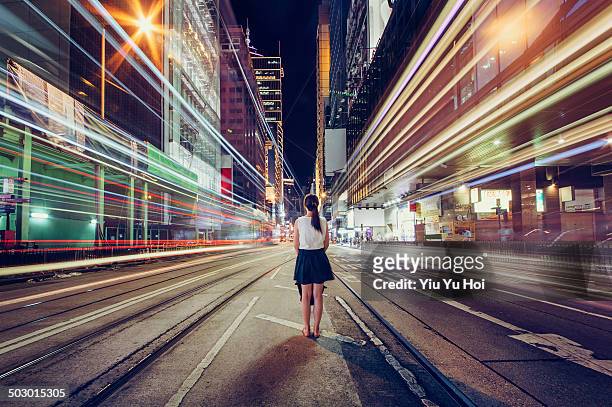 young woman is lost in metropolitan city at night - lange sluitertijd stockfoto's en -beelden