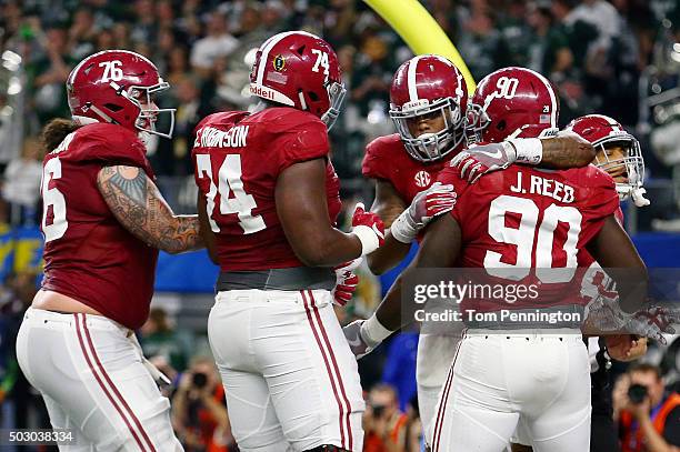 Derrick Henry of the Alabama Crimson Tide celebrates scoring a touchdown in the second quarter with teammates offensive lineman Cam Robinson and...