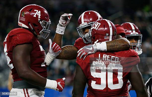 Derrick Henry of the Alabama Crimson Tide celebrates scoring a touchdown in the second quarter with teammates offensive lineman Cam Robinson and...