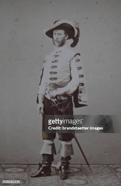 Young man in medieval costume with hat; Sword, and boots; probably for a celebration with vivant tableaux. Full figure. About 1865. Carte-de-visite...