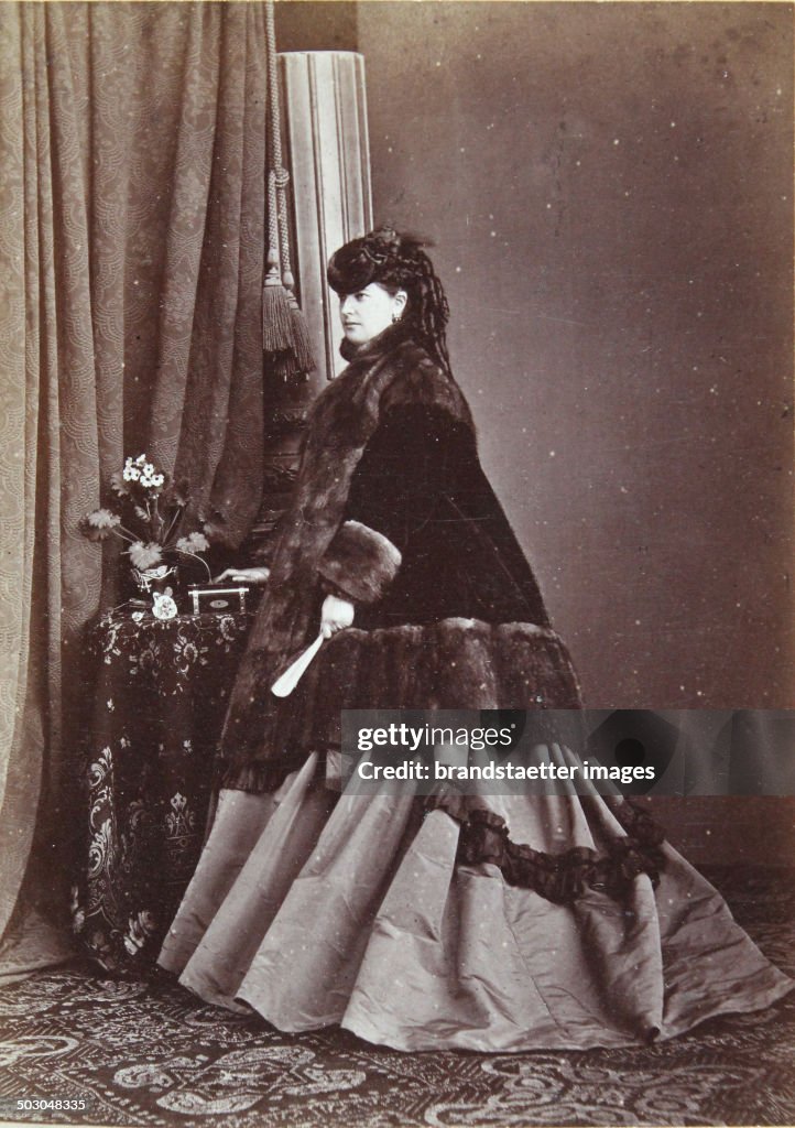 Lady In Semi Profile With Hood; Fur-Trimmed Overcoat And Dark Apparel (In The Left Hand A Fan). Full Figure. About 1865. Photograph By Photographer And Lithographer August Red. Linz