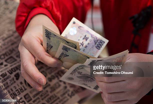 An employee counts Japanese yen notes as he sells a 'lucky bag' at a Bic Camera Inc. Store on January 1, 2016 in Tokyo, Japan. Many Japanese retail...