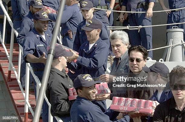 Television personality Jay Leno, singers Chris Isaak and Dwight Yoakam and comedian Cedric The Entertainer helping sailors load supplies onboard...