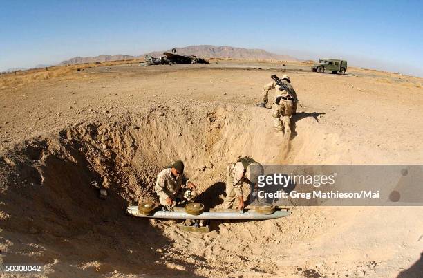 At a forward operating base in Kandahar, Afghanistan, Explosive Ordnance Disposal personnel prepare charges to blow up stockpiled bombs left behind...