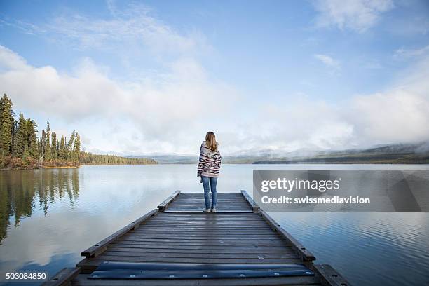 serene woman stands on pier relaxing by the lake - pier stock pictures, royalty-free photos & images
