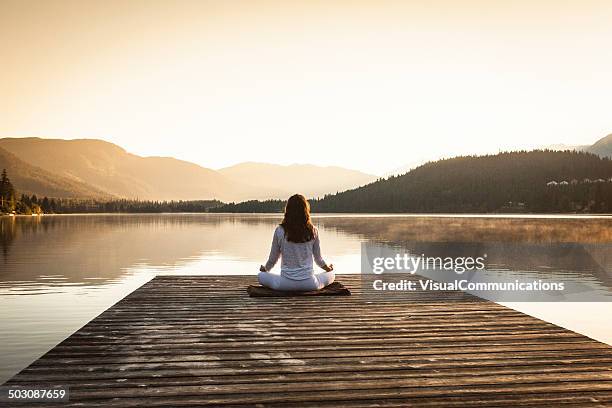 mujer meditando al lago. - meditation outdoors fotografías e imágenes de stock