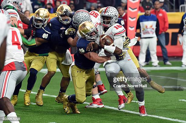 Linebacker Joe Schmidt of the Notre Dame Fighting Irish hits quarterback J.T. Barrett of the Ohio State Buckeyes during the first quarter of the...