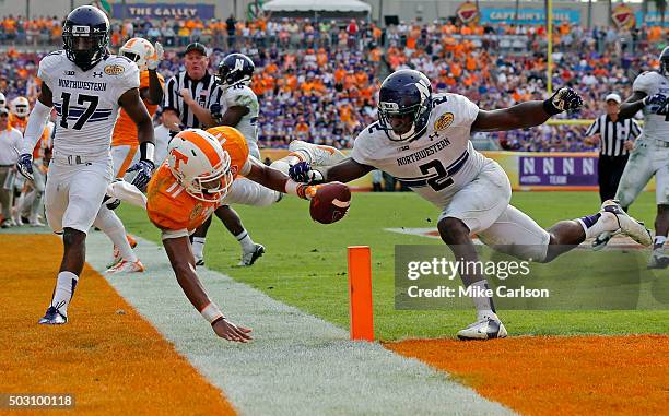 Joshua Dobbs of the Tennessee Volunteers dives past the defense of Traveon Henry of the Northwestern Wildcats to score a touchdown during the second...