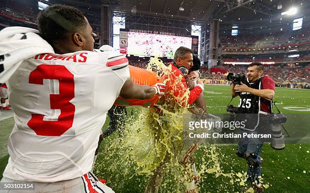 Wide receiver Michael Thomas of the Ohio State Buckeyes and running back Ezekiel Elliott douse head coach Urban Meyer with Gatorade after the fourth...