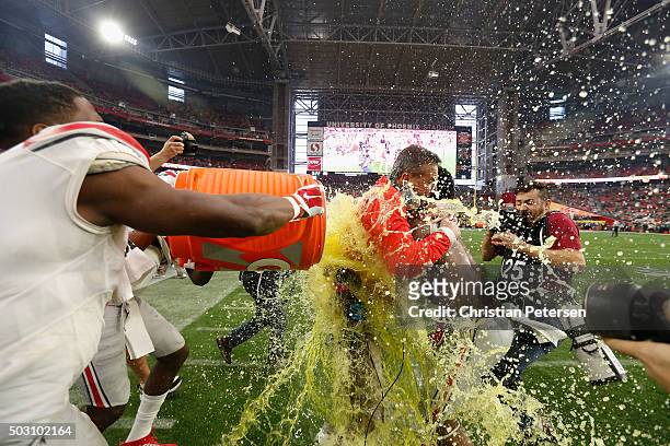 Wide receiver Michael Thomas of the Ohio State Buckeyes and running back Ezekiel Elliott douse head coach Urban Meyer with Gatorade after the fourth...