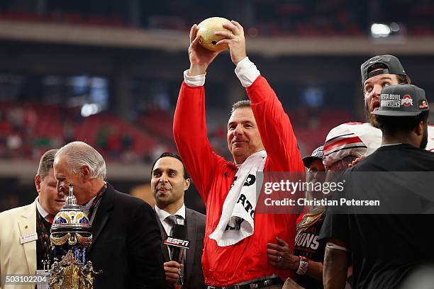 Head coach Urban Meyer of the Ohio State Buckeyes holds up the BattleFrog Fiesta Bowl trophy after defeating the Fighting Irish 44-28 at University...