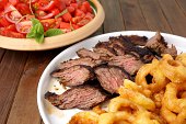Flank steak with fries onion rings and salad