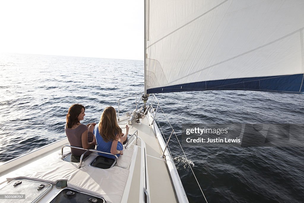 Friends looking out at ocean on front of sailboat