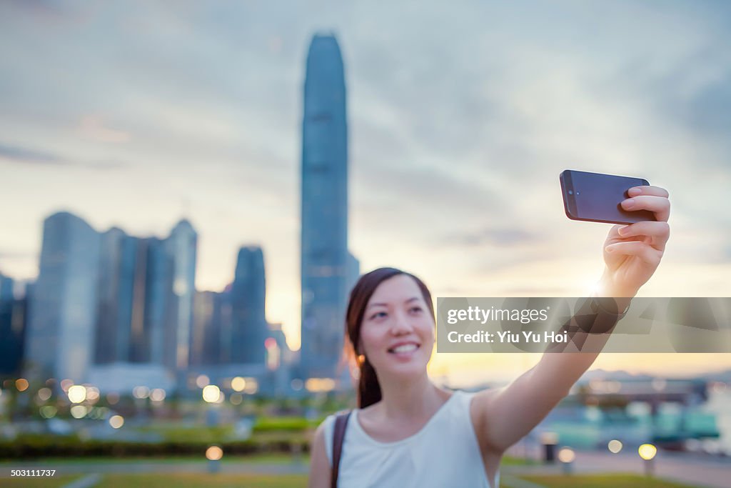 Smiling young lady taking selfie on smartphone