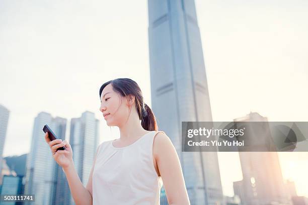 busy businesswoman text messaging in modern city - sleeveless stock pictures, royalty-free photos & images