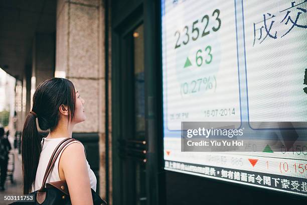 asian businesswoman looking at stock quote board - oberteil stock-fotos und bilder