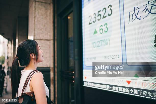 asian businesswoman looking at stock quote board - exclusive dealing stockfoto's en -beelden