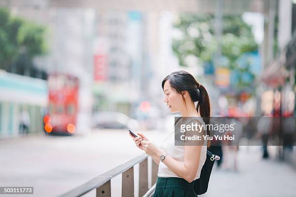 busy office lady texting on smartphone in city - sleeveless ストックフォトと画像