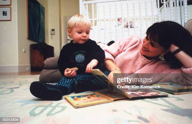 Author Dr. Nancy Snyderman reading to son Charlie on bedroom floor at home.