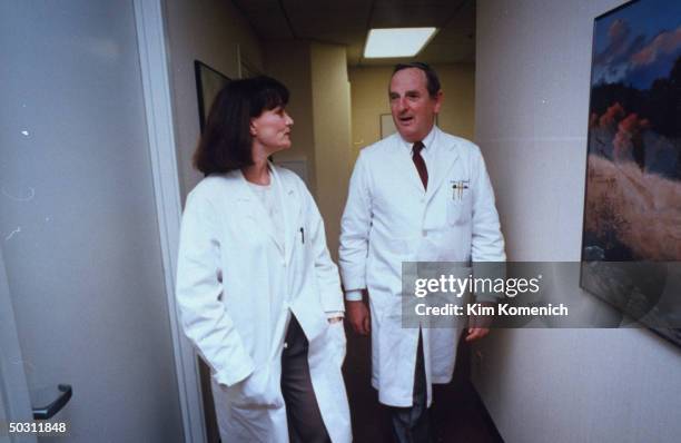 Author Dr. Nancy Snyderman chatting w. Partner Dr. Jim Klein as they walk through hallway of their office.