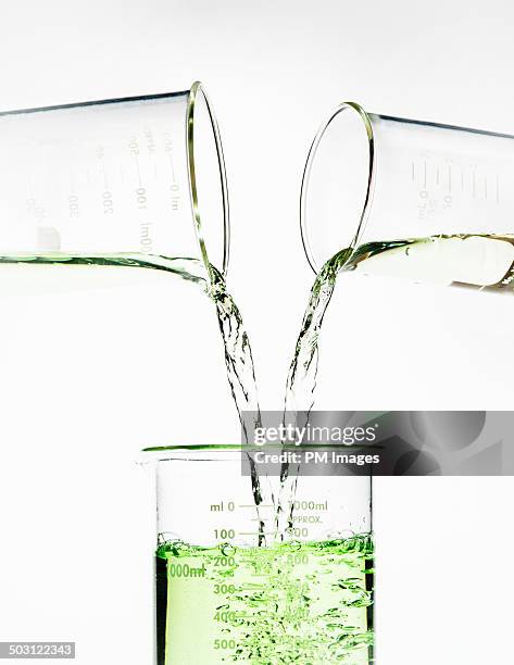 beakers pouring liquid larger beaker - reazione chimica foto e immagini stock