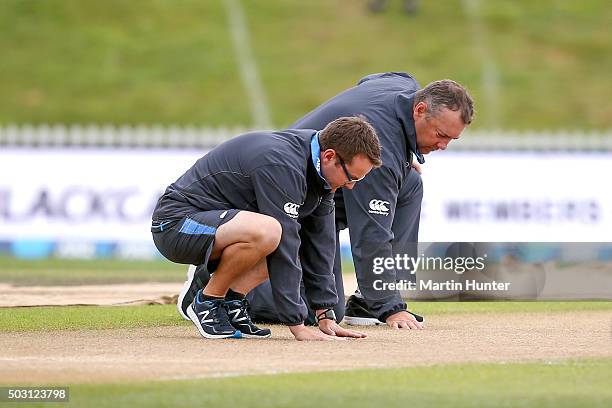 New Zealand coaches Mike Hessen and Craig McMillan inspect the pitch as rain delays the start of play for game four of the One Day International...