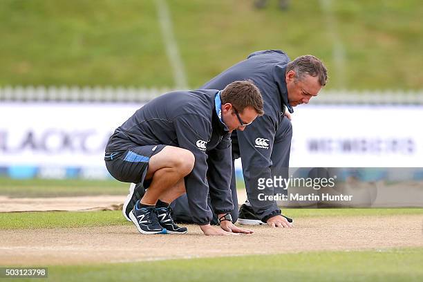 New Zealand coaches Mike Hessen and Craig McMillan inspect the pitch as rain delays the start of play for game four of the One Day International...