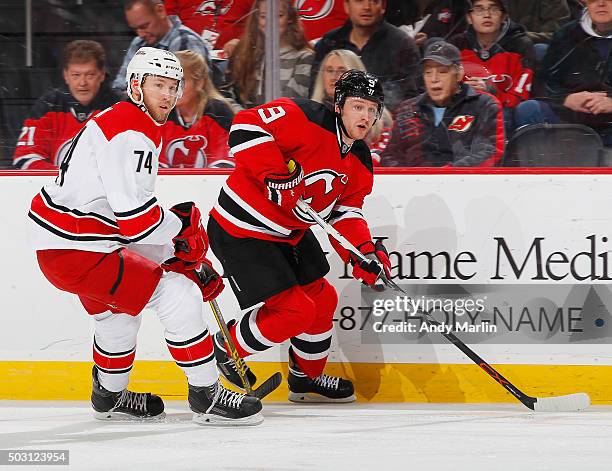 Jiri Tlusty of the New Jersey Devils and Jaccob Slavin of the Carolina Hurricanes skate for position during the game at the Prudential Center on...