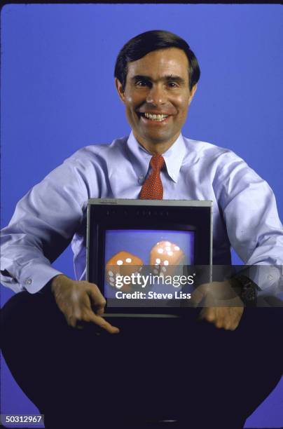 Venture Capitalist David Croll sitting on stool holding color TV screen in lap with picture of dice on it.