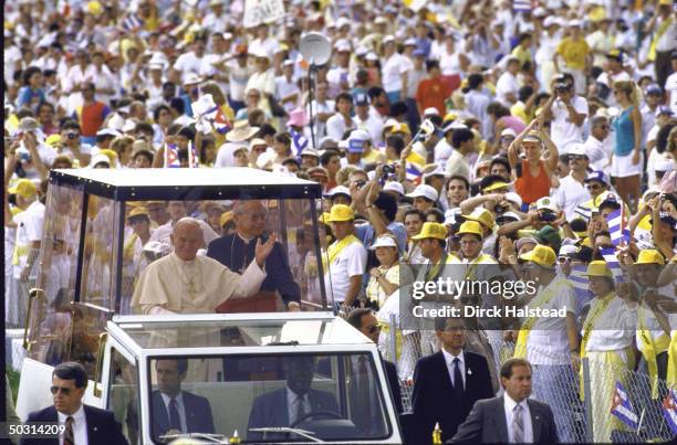 Pope John Paul II waving to the crowd from inside the Popemobile as he arrives to celebrate outdoor mass.