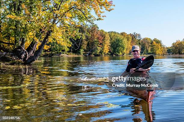 smiling male kayaker paddling in front of beautiful fall foliage - ottawa fall stock pictures, royalty-free photos & images