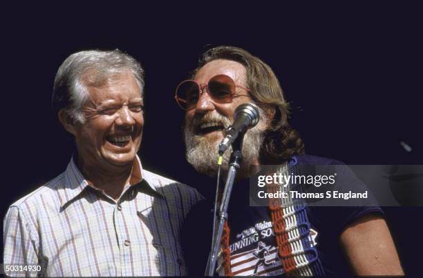 Former US President Jimmy Carter smiling broadly and standing next to Country and Western singer Willie Nelson at concert during Plains, Georgia's...