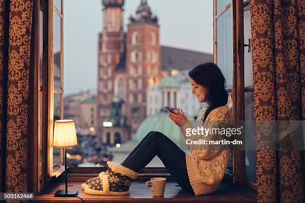 woman texting on the window sill - krakow poland stockfoto's en -beelden