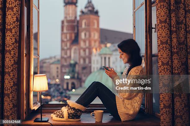 mulher mandando mensagens no celular no peitoril de janela - cracóvia - fotografias e filmes do acervo