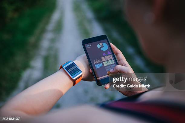 woman synchronising smartwatch and mobile phone. - smartwatch stock-fotos und bilder