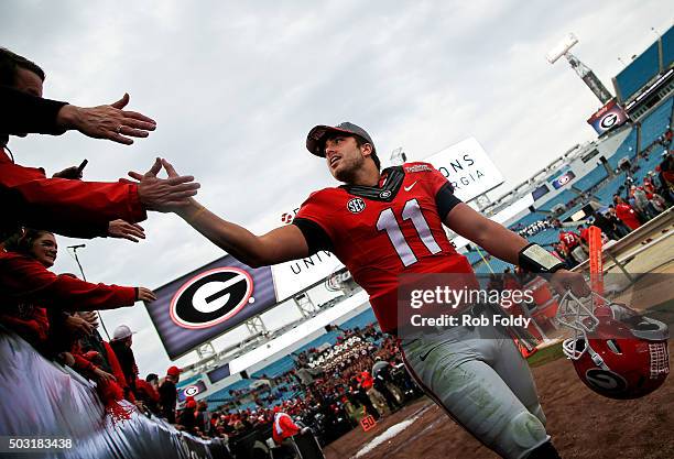 Greyson Lambert of the Georgia Bulldogs slaps hands with fans after defeating the Penn State Nittany Lions in the TaxSlayer Bowl game at EverBank...