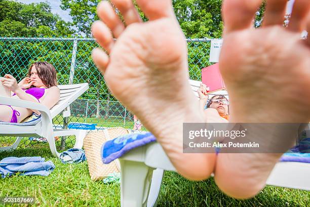 kleines mädchen liest ein buch in der chaise lounge - teenage girls barefoot stock-fotos und bilder